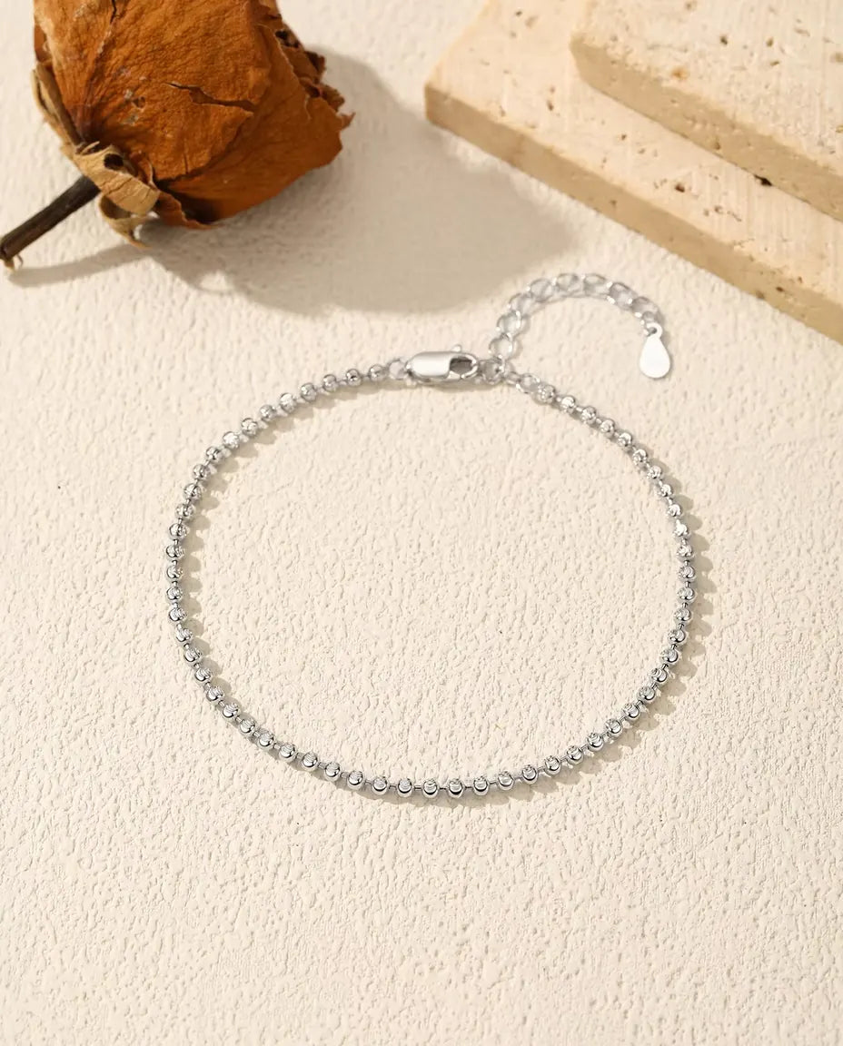Facettiertes Kugelarmband aus 925 Sterlingsilber - flach auf heller Strukturfläche mit Verschluss und Verlängerungskette