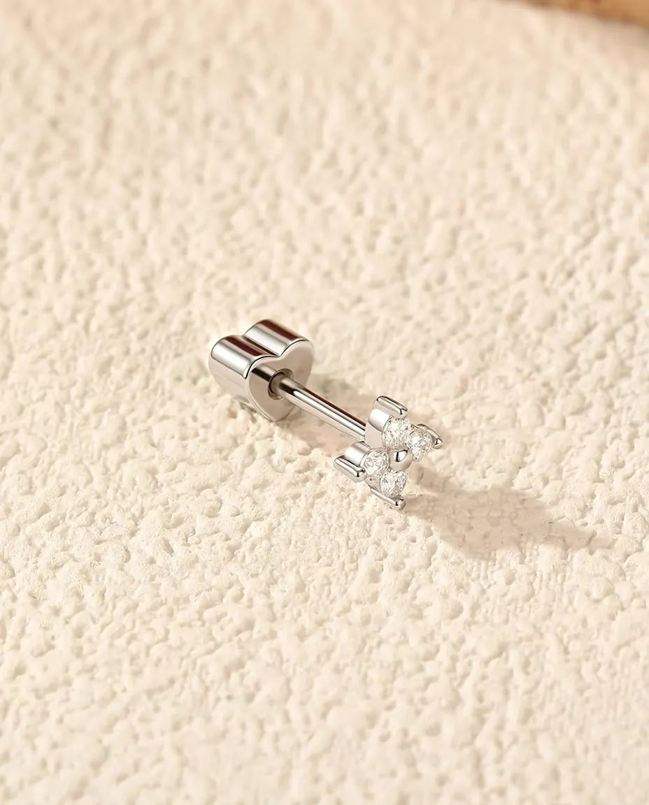 Moissanit Kleeblatt Ohrstecker mit vier Steinen aus 925 Sterlingsilber - seitlich liegend auf heller Strukturfläche, herzförmiger Verschluss auf dem Stift