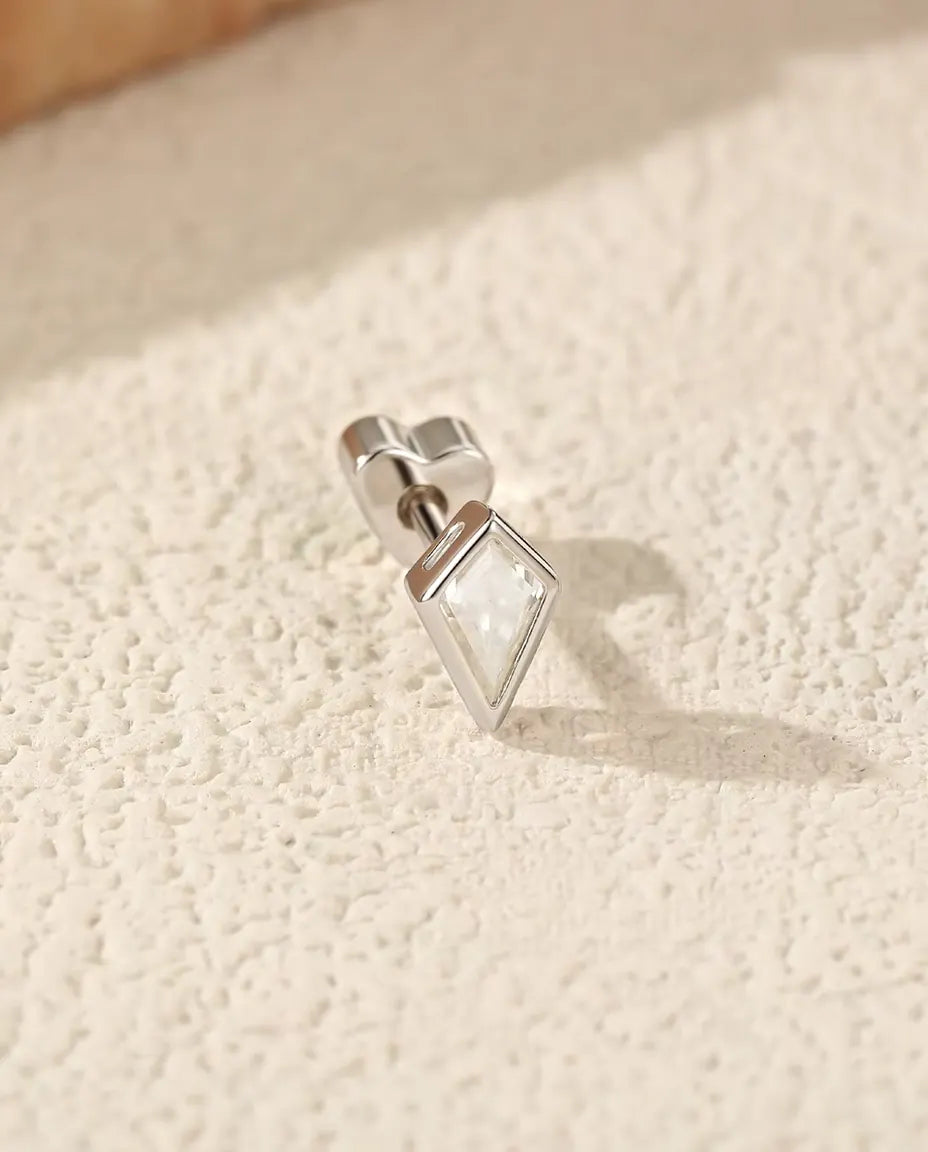 Moissanit Ohrstecker im Drachenschliff aus 925 Sterlingsilber - seitlich liegend auf heller Strukturfläche, herzförmiger Verschluss auf dem Stift