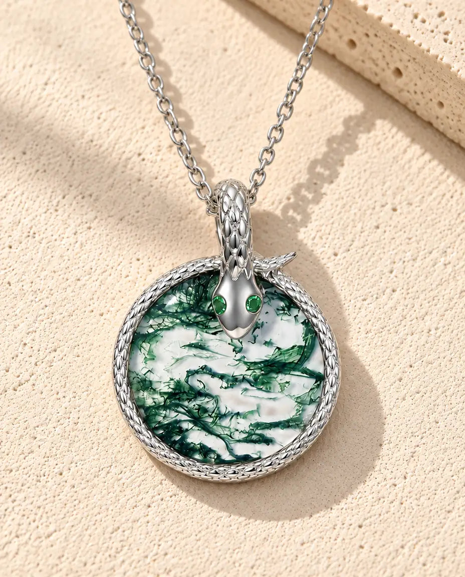 Moosachat Schlangen Kette aus 925 Sterlingsilber - auf heller Strukturfläche neben einem Travertinblock liegend