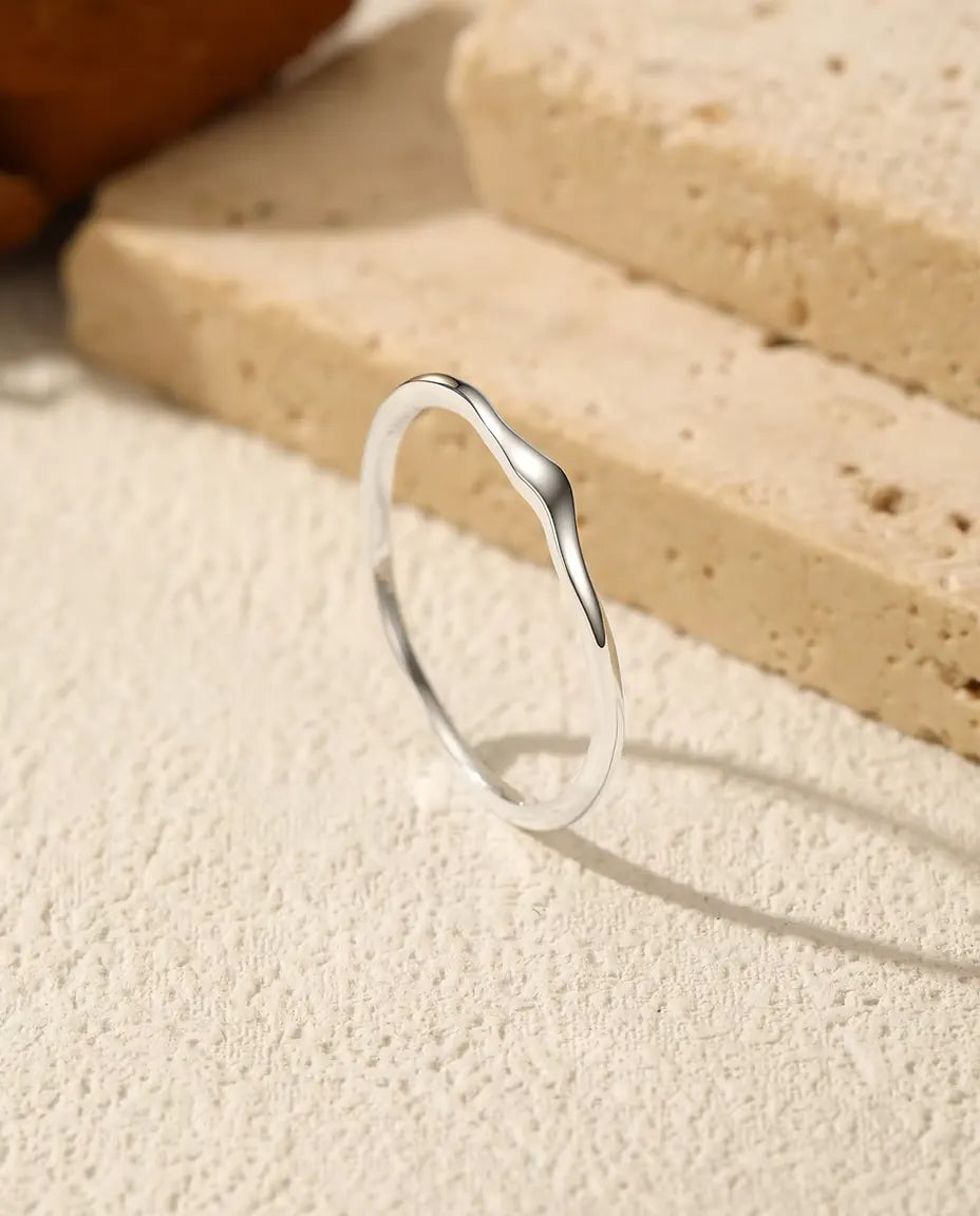 Welliger Stapelring aus 925 Sterlingsilber - aufrecht stehend auf heller Strukturfläche