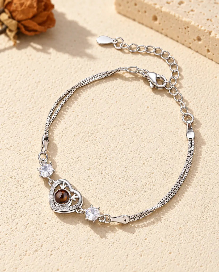 Armband mit Bild im Stein: silberfarbenes Herz mit Geweih und zwei Zirkonia an feiner Doppelkette auf hellem Gips