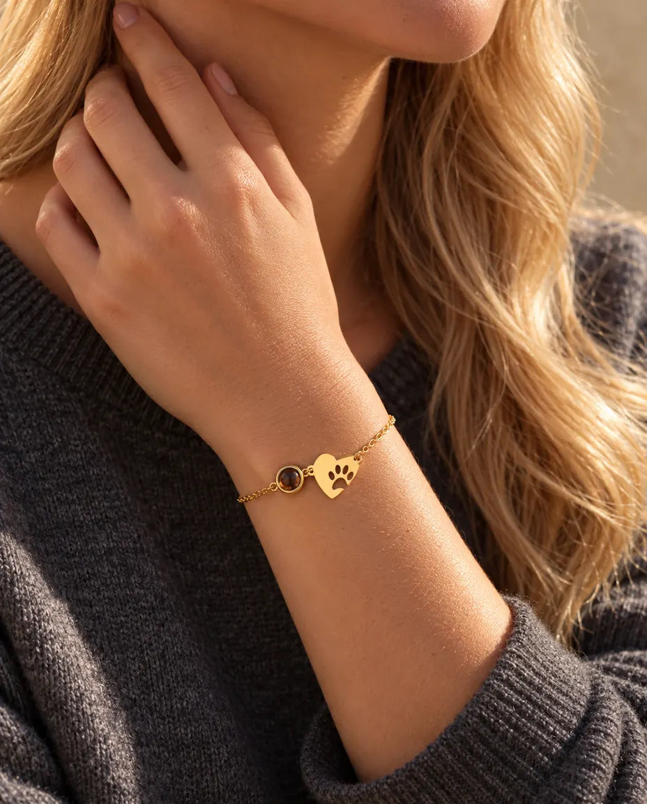 Nahaufnahme des goldfarbenen Pfoten-Herz-Armbands am Handgelenk, Fingerspitzen seitlich am Hals