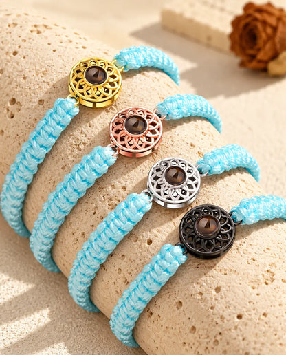 Armbänder mit hellblauem Flechtband nebeneinander auf Travertin, der Charm in jeder Farbe