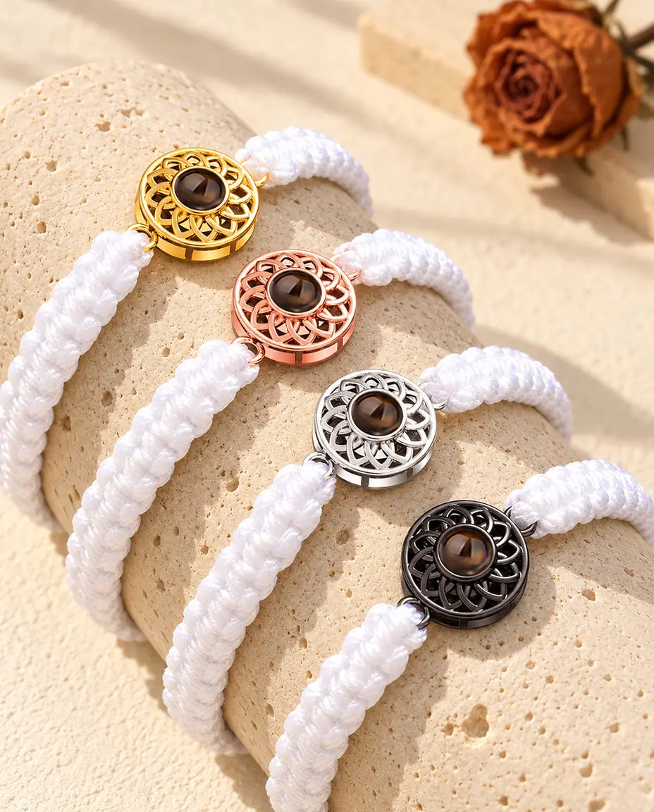 Vier Armbänder mit weissem Flechtband und Rund-Charm in Gold, Roségold, Silber und Schwarz auf Travertin