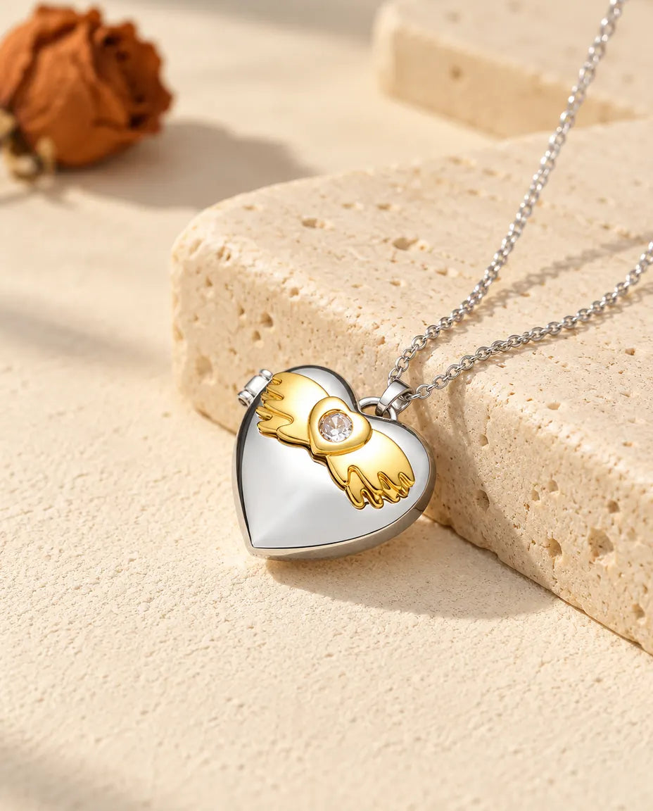 Personalisiertes Herz-Foto-Medaillon mit Engelsflügeln silberfarben mit goldfarbenen Engelsflügeln, auf einem Travertinblock