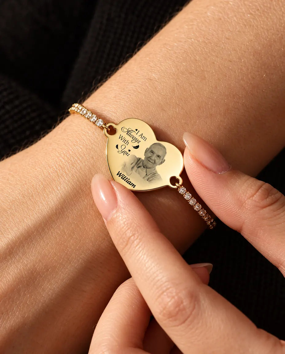 Fingerspitzen halten das goldfarbene gravierte Foto-Herz am Handgelenk