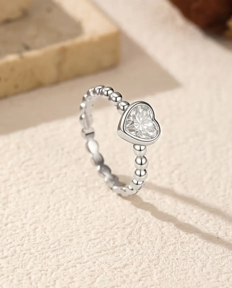 Herz Moissanit Ring aus 925 Sterlingsilber - aufrecht stehend auf heller Strukturfläche