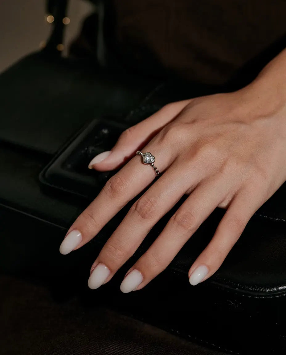 Herz Moissanit Ring aus 925 Sterlingsilber - an einer Hand auf einer schwarzen Tasche getragen