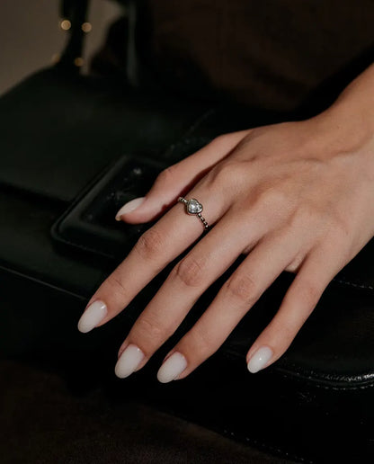 Herz Moissanit Ring aus 925 Sterlingsilber - an einer Hand auf einer schwarzen Tasche getragen