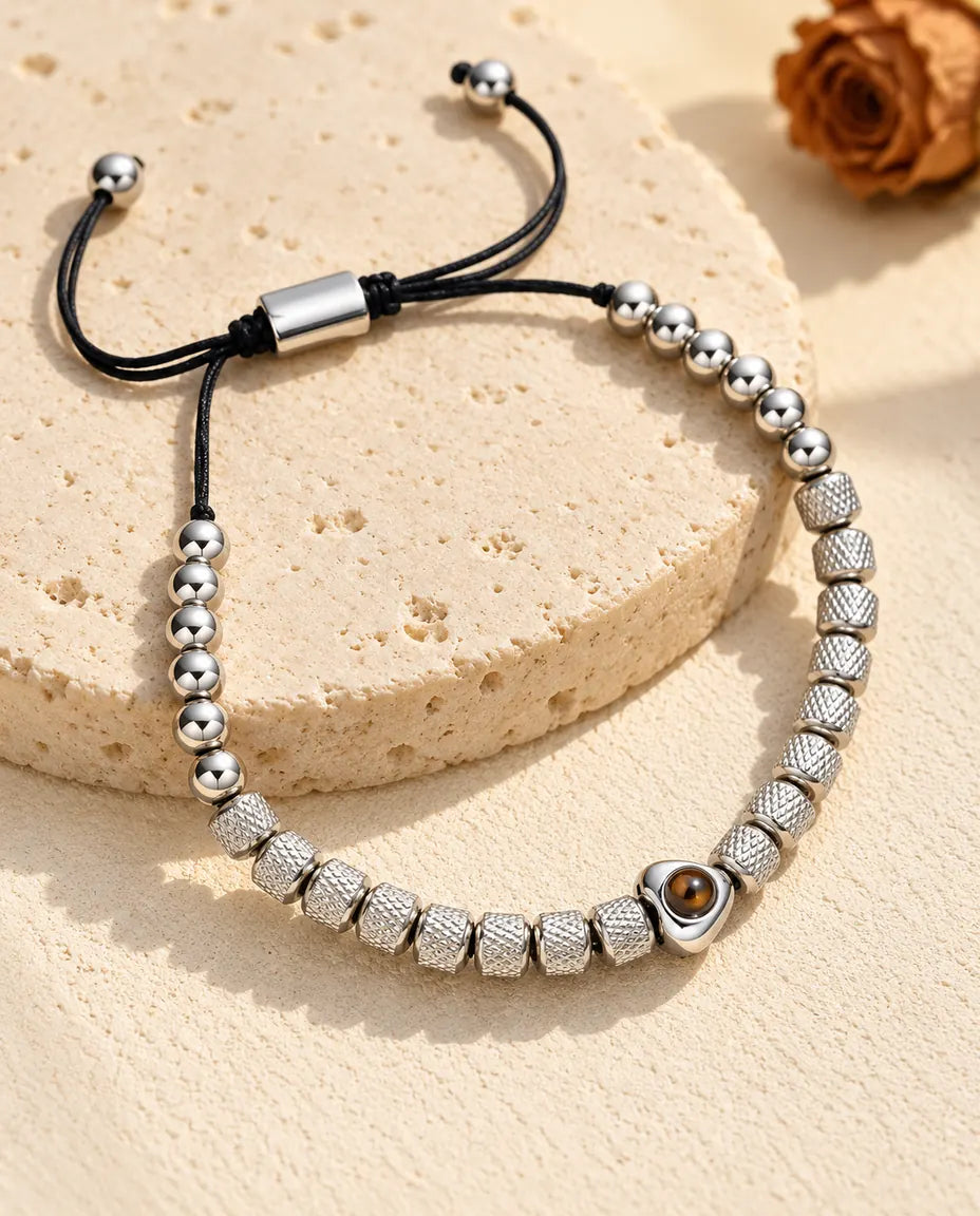 Personalisiertes Perlenarmband mit Herzperle und Bild im Stein, silberfarben, auf einer Travertinplatte