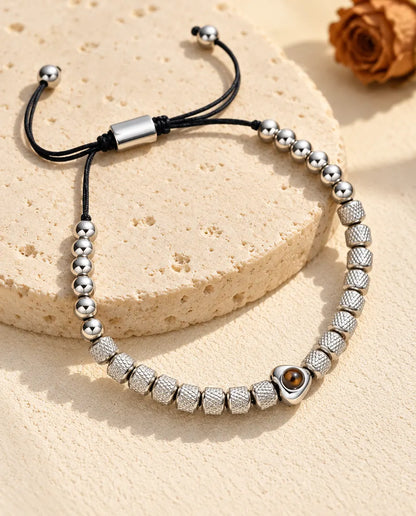 Personalisiertes Perlenarmband mit Herzperle und Bild im Stein, silberfarben, auf einer Travertinplatte