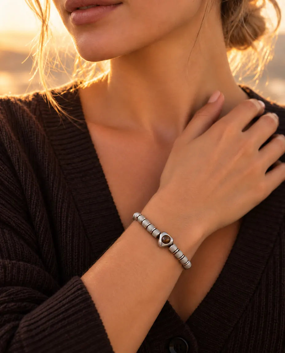 Frau mit der Hand am Schlüsselbein trägt das silberfarbene Perlenarmband mit Herzperle