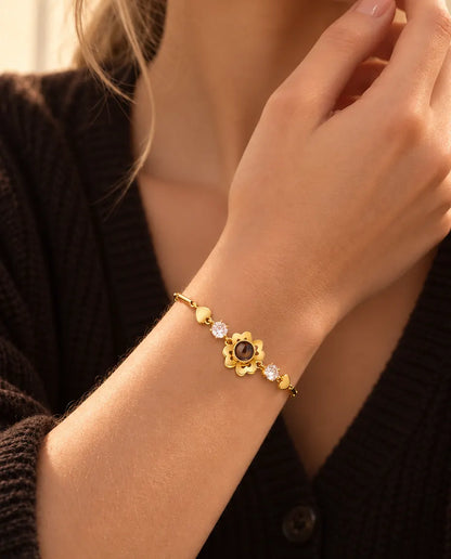 Nahaufnahme des goldfarbenen Kleeblatt-Armbands mit kleinen Herzen am Handgelenk nahe dem Kinn