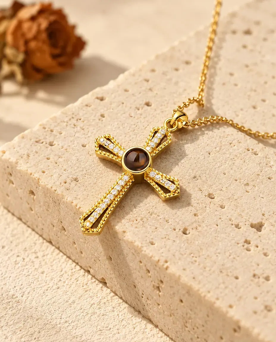 Goldfarbenes Kreuz mit offenen Armen und einer Reihe Zirkonia auf Travertin