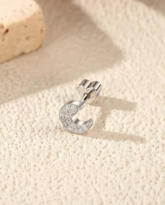 Pavé Moissanit Halbmond Ohrstecker aus 925 Sterlingsilber - seitlich liegend auf heller Strukturfläche, herzförmiger Verschluss auf dem Stift