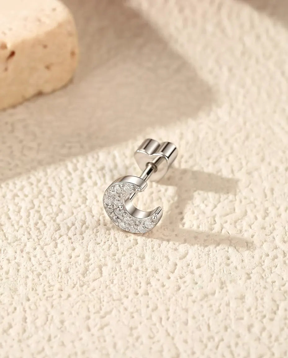Pavé Moissanit Halbmond Ohrstecker aus 925 Sterlingsilber - seitlich liegend auf heller Strukturfläche, herzförmiger Verschluss auf dem Stift