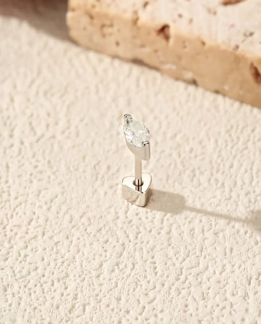 Moissanit Ohrstecker im Marquiseschliff aus 925 Sterlingsilber - aufrecht auf dem herzförmigen Verschluss stehend, auf heller Strukturfläche