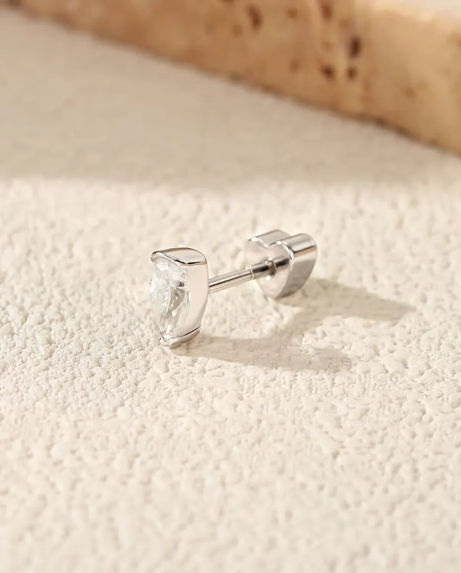 Moissanit Ohrstecker im Tropfenschliff aus 925 Sterlingsilber - auf heller Strukturfläche neben einer Travertinplatte
