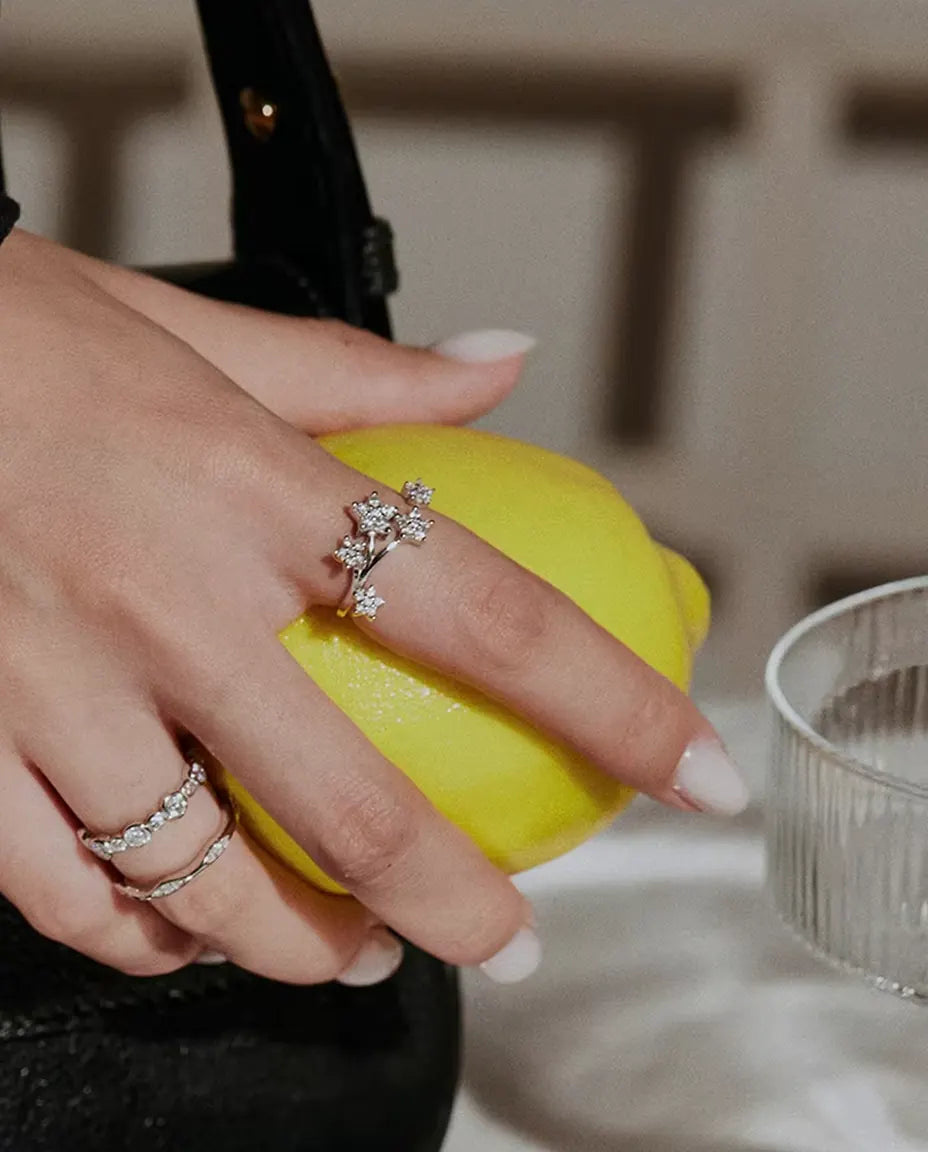 Moissanit Ring mit Sternen aus 925 Sterlingsilber - zusammen mit weiteren Ringen getragen, Hand hält eine Zitrone
