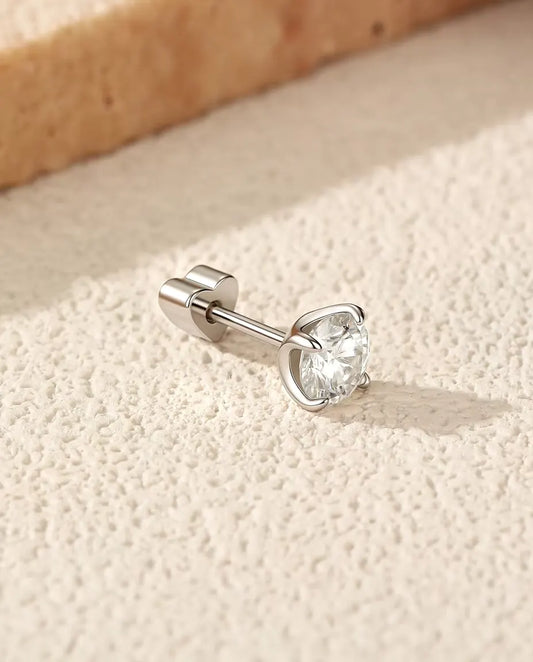 Runde Moissanit Solitär-Ohrstecker mit vier Krappen aus 925 Sterlingsilber - seitlich liegend auf heller Strukturfläche, herzförmiger Verschluss auf dem Stift