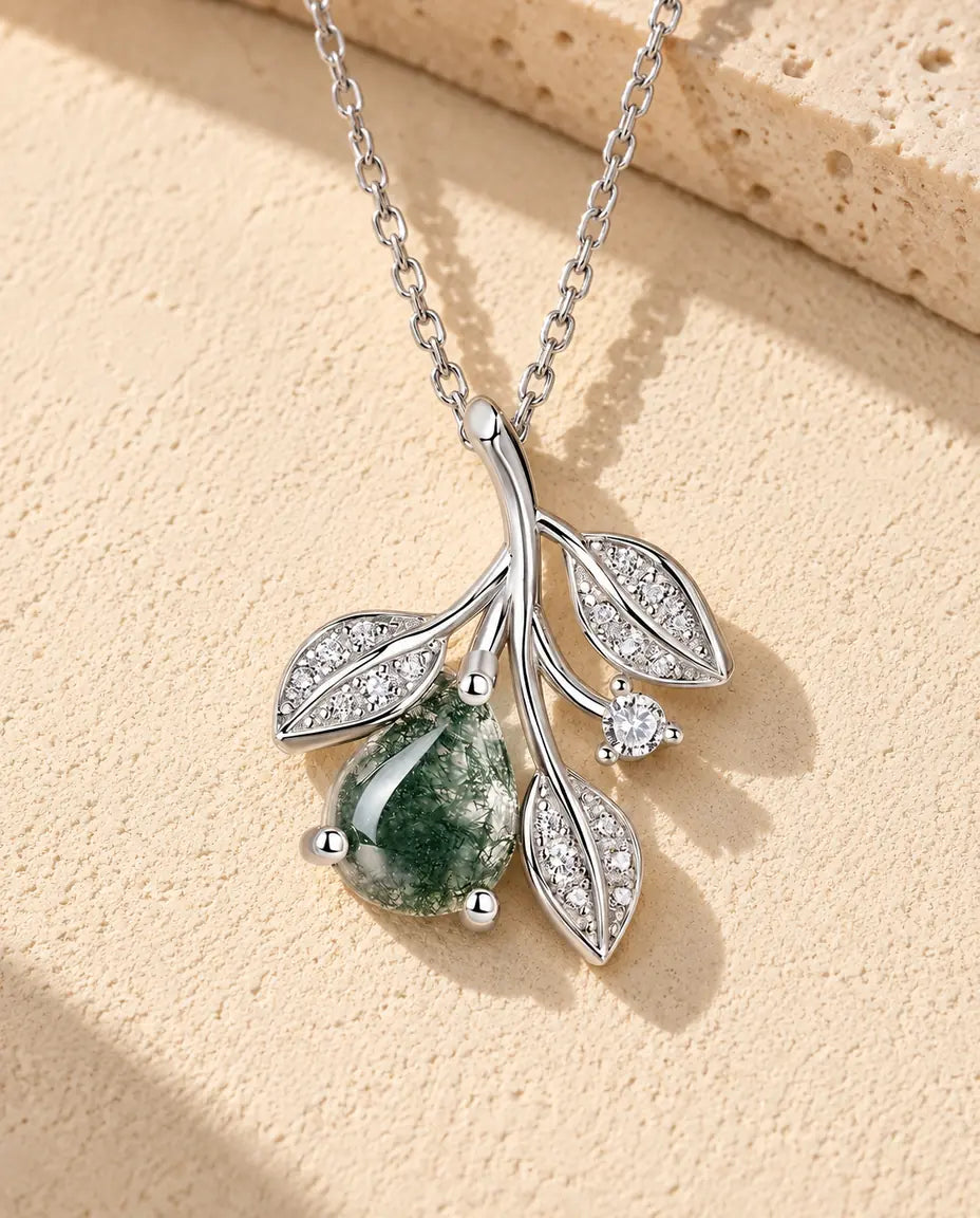Moosachat Blatt Kette aus 925 Sterlingsilber - auf heller Strukturfläche neben einem Travertinblock liegend