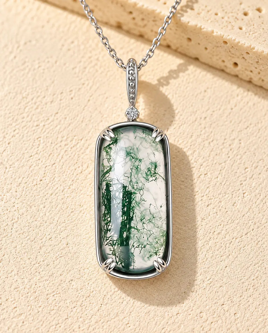 Moosachat Kette mit Rechteck-Anhänger aus 925 Sterlingsilber - auf heller Strukturfläche neben einem Travertinblock liegend