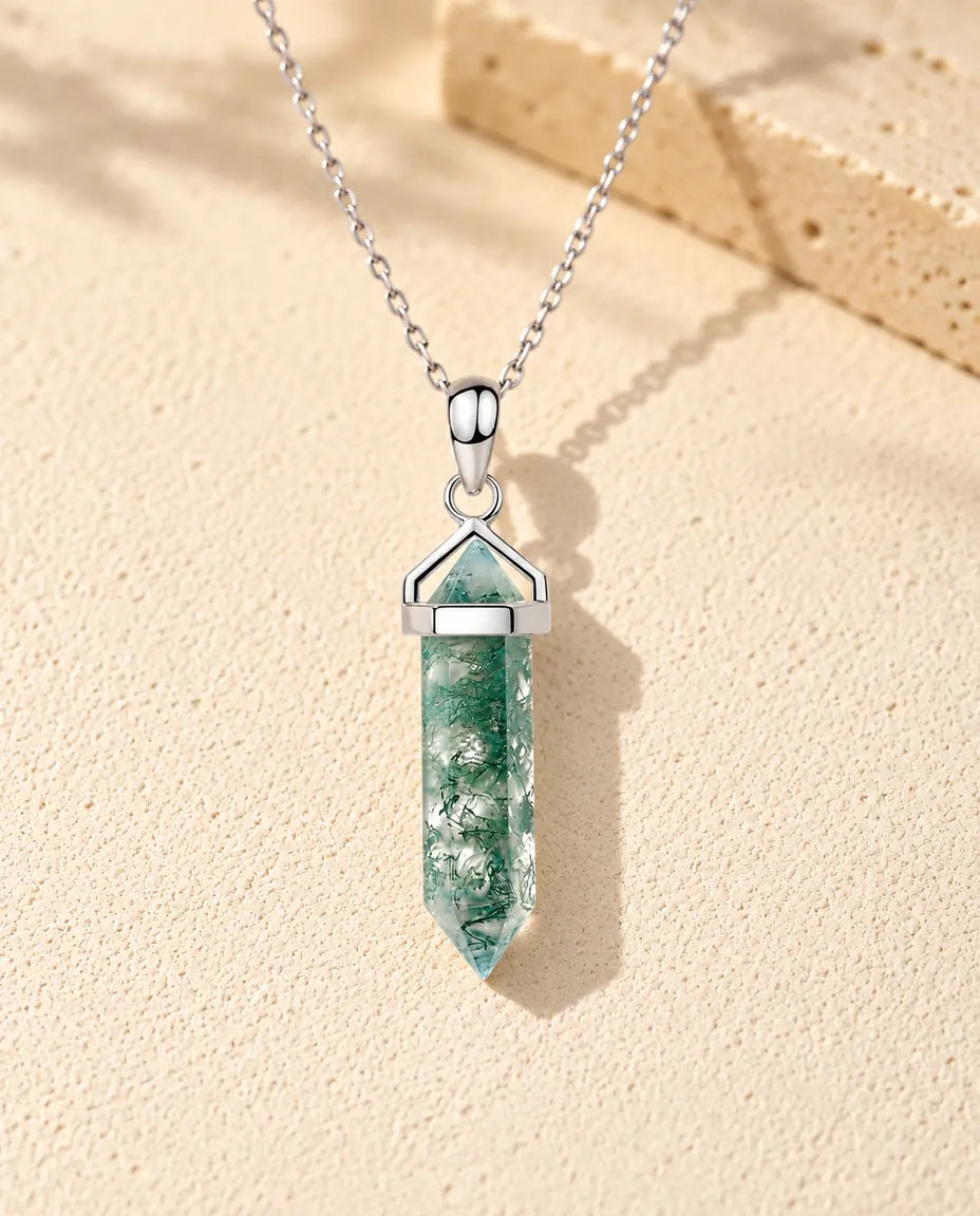 Moosachat Kette mit Sechseck-Spitze aus 925 Sterlingsilber - auf heller Strukturfläche neben einem Travertinblock liegend