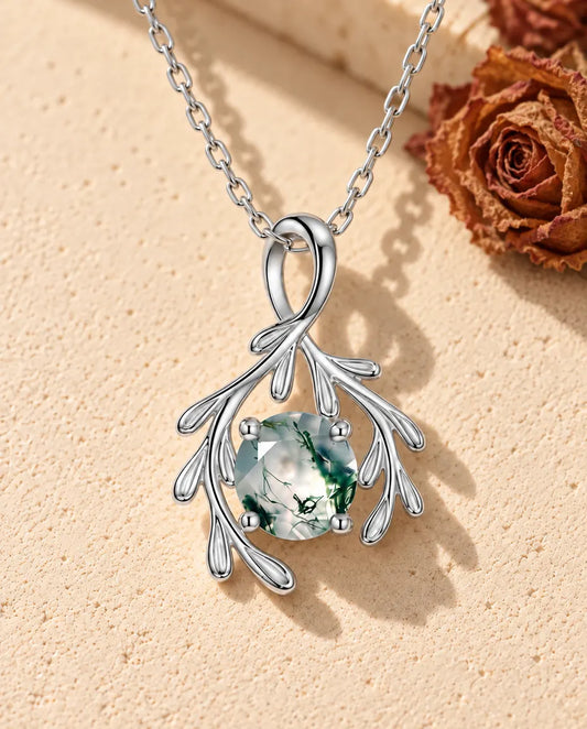 Moosachat Zweig Kette aus 925 Sterlingsilber - auf heller Strukturfläche neben einem Travertinblock liegend