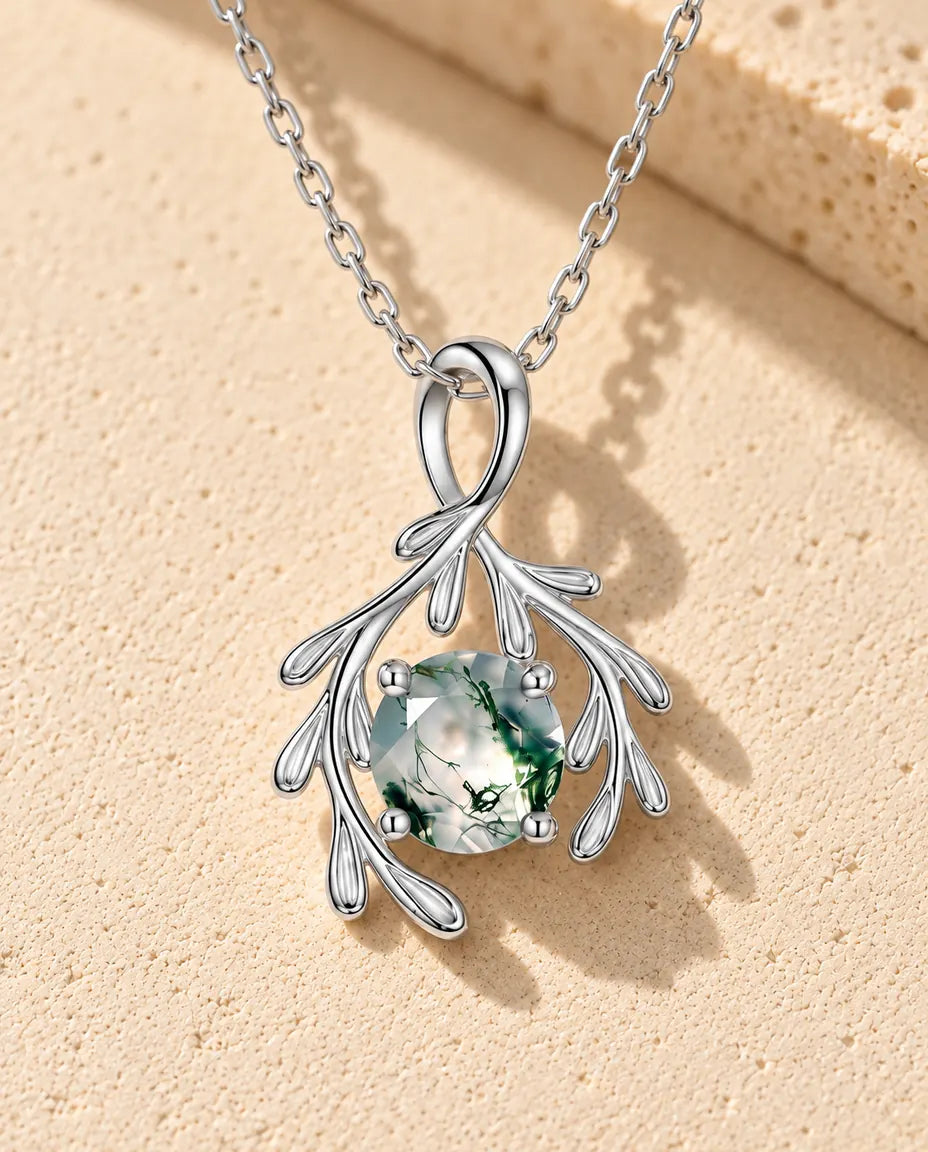 Moosachat Zweig Kette aus 925 Sterlingsilber - auf heller Strukturfläche neben einem Travertinblock liegend