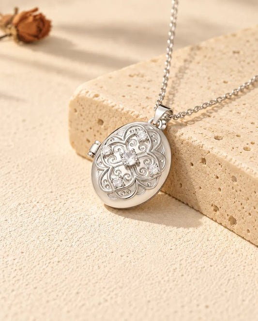 Personalisiertes ovales Foto-Medaillon in Silber mit Filigran-Blume und Zirkonia, an einen Travertinblock gelehnt