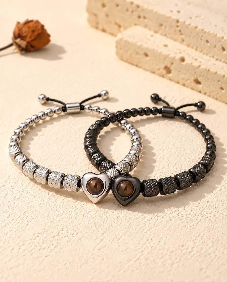 Silberfarbenes und schwarzes Herzperlen-Armband ineinander verschlungen wie zwei Ringe