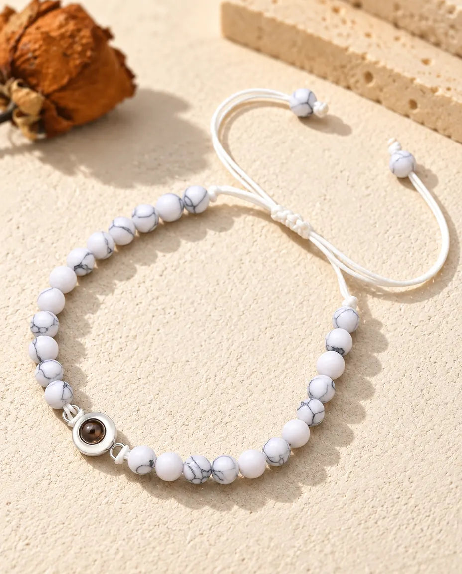 Weiss marmoriertes Perlenarmband mit silberfarbenem Charm und Schiebeknoten