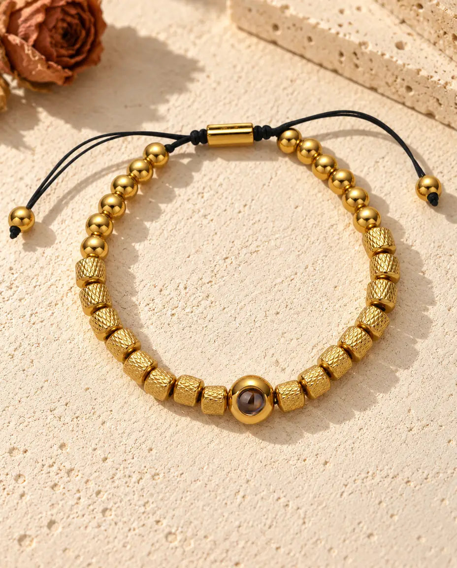 Draufsicht auf das goldfarbene Perlenarmband mit Bild im Stein und Schiebekordel