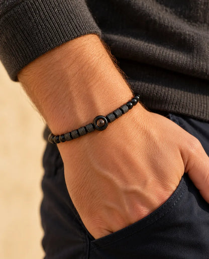 Mann trägt das schwarze Perlenarmband mit Bild im Stein, die Hand in der Hosentasche