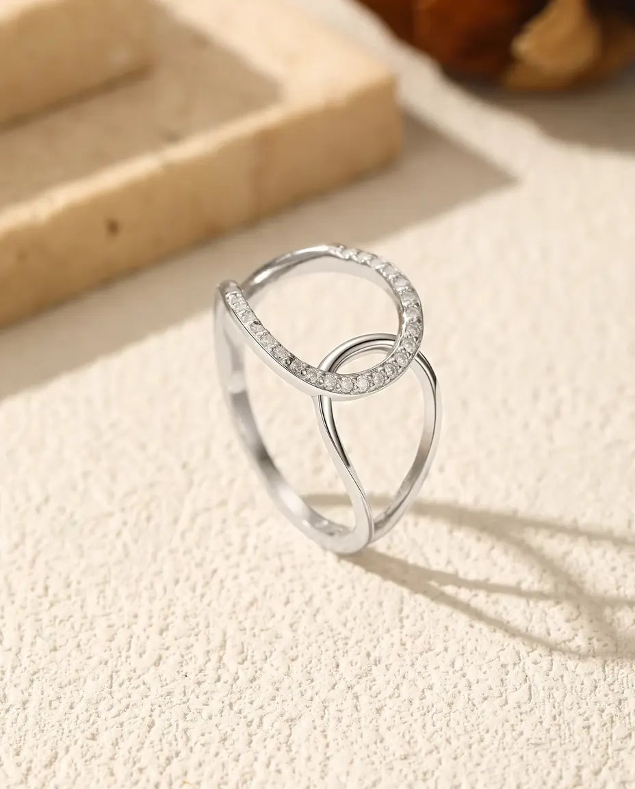 Ring mit verschlungenen Kreisen aus 925 Sterlingsilber - aufrecht stehend auf heller Strukturfläche