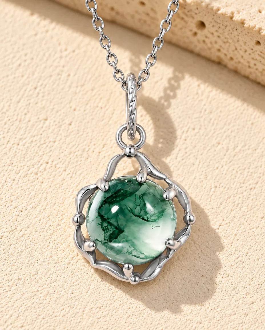 Runde Moosachat Kette aus 925 Sterlingsilber - auf heller Strukturfläche neben einem Travertinblock liegend