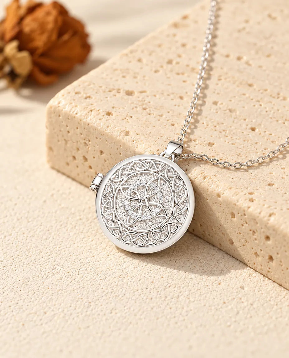 Silberfarbenes rundes Foto-Medaillon mit keltischem Knoten als personalisierte Kette, an einen Travertinblock gelehnt
