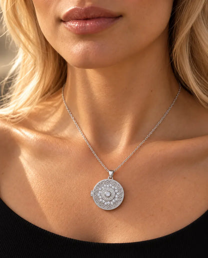 Frau im schwarzen Strickoberteil trägt das silberfarbene runde Foto-Medaillon mit Mandala-Blume