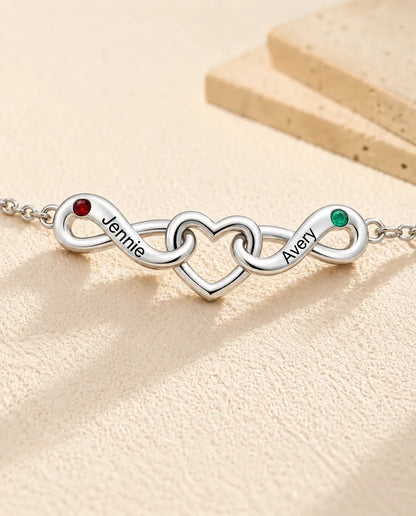 Personalisiertes Unendlichkeit Armband mit 2 Namen - zwei Unendlichkeitsschleifen um ein Herz - Nahaufnahme der gravierten Namen und Geburtssteine