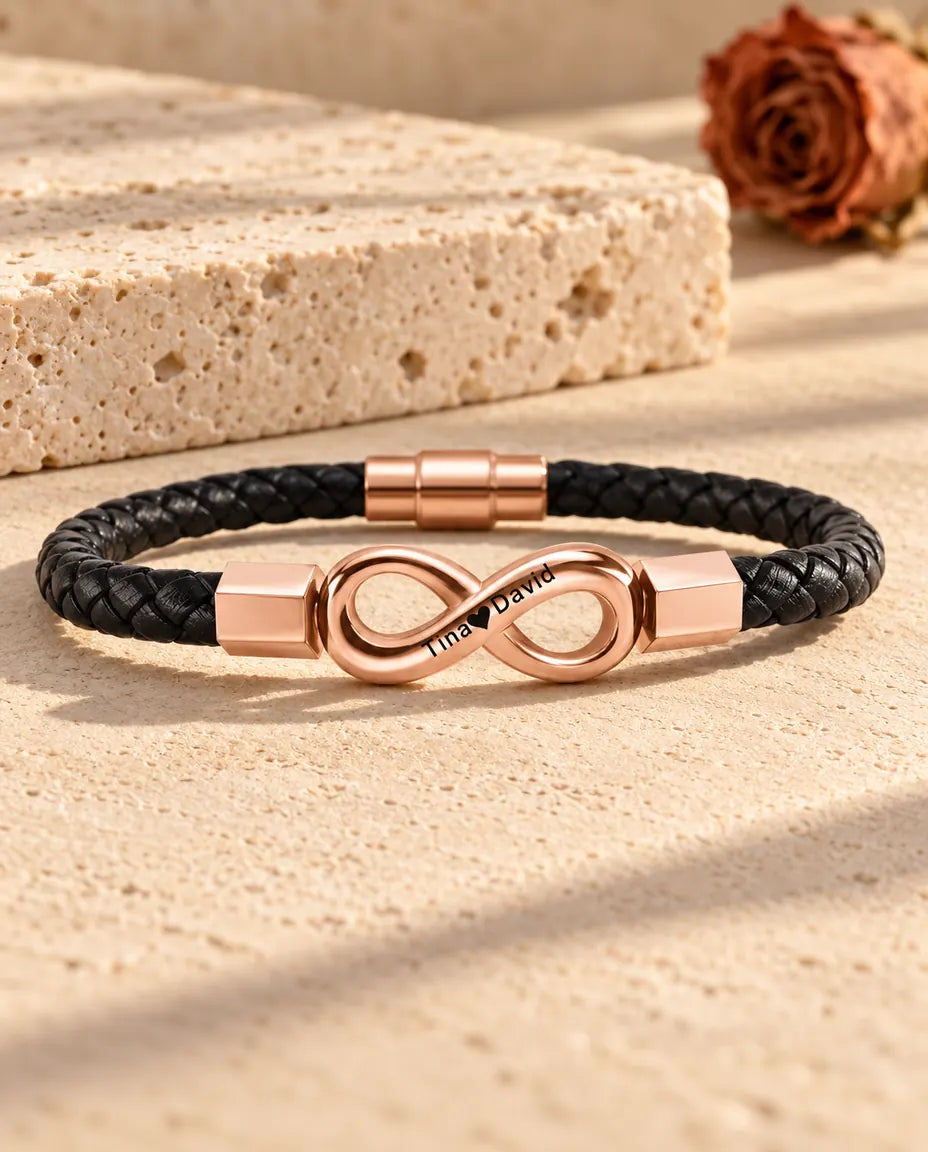 Roségoldfarbenes graviertes Unendlichkeitszeichen an einem schwarzen Armband aus geflochtenem Kunstleder