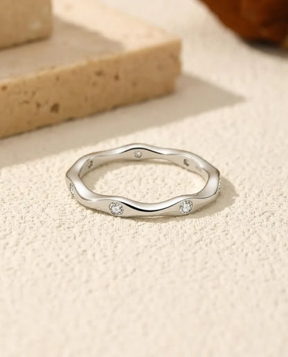 Welliger Moissanit Ring aus 925 Sterlingsilber - flach liegend auf heller Strukturfläche