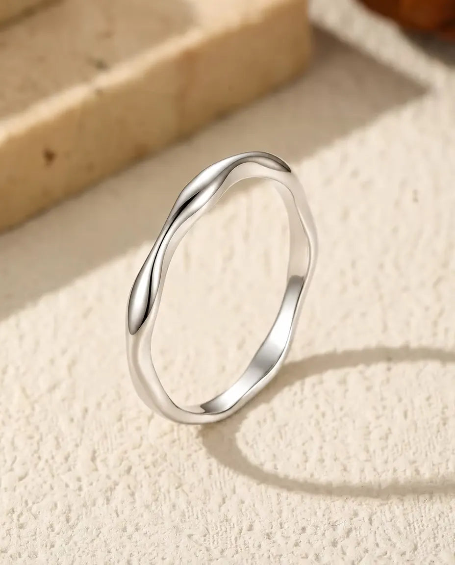 Welliger Ring aus 925 Sterlingsilber - aufrecht stehend auf heller Strukturfläche