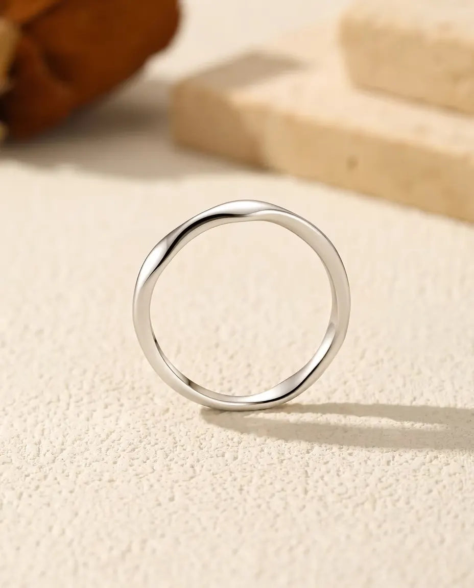 Welliger Ring aus 925 Sterlingsilber - von vorn, aufrecht auf heller Strukturfläche