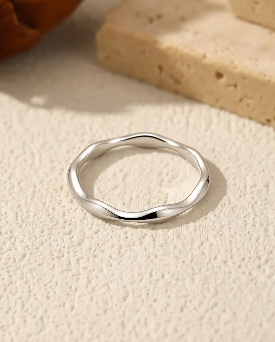 Welliger Ring aus 925 Sterlingsilber - flach liegend auf heller Strukturfläche