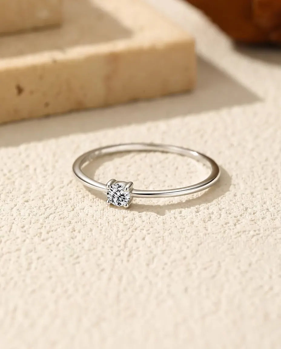 Zarter Moissanit Solitär Ring aus 925 Sterlingsilber - flach liegend auf heller Strukturfläche