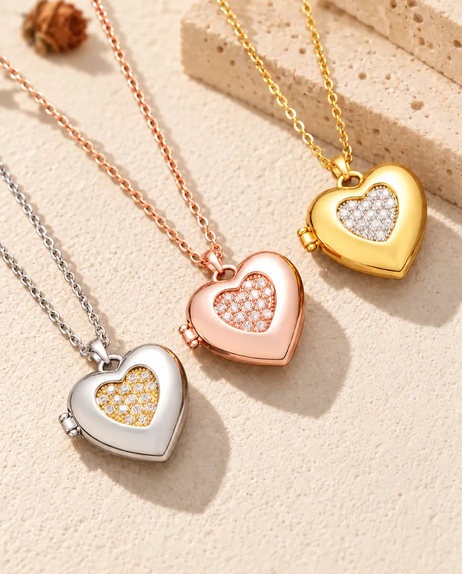 Zweifarbiges Herz-Foto-Medaillon in Silber-, Roségold- und Goldfarbe schräg auf cremefarbenem Putz